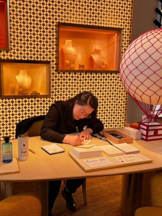 Cathy entrain de rédiger des cartes de voeux pour les clients de Louis Vuitton